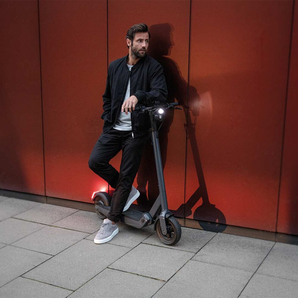 lässiger Mann vor rotem Hintergrund in der Stadt Egret PRO escooter elektroroller eroller